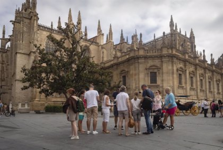 Un grupo de turistas ante la fachada de la Catedral. A 11 de agosto de 2022, en Sevilla (Andalucía, España).