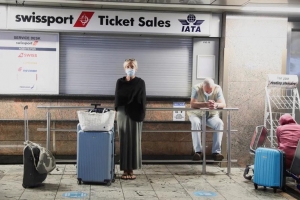 Los pasajeros esperan la confirmaci&oacute;n de sus vuelos frente al mostrador de venta de billetes de Swissport.