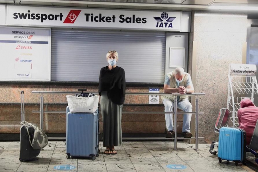 Los pasajeros esperan la confirmaci&oacute;n de sus vuelos frente al mostrador de venta de billetes de Swissport.