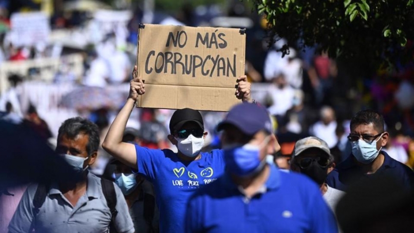 Un hombre sostiene un cartel que dice &quot;No más corrupción&quot; durante una protesta contra el presidente Nayib Bukele y por un poder judicial independiente, 12 de diciembre de 2021.