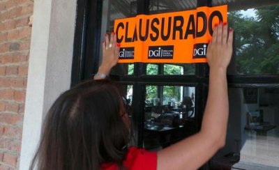  Funcionarios de la DGI colocan los carteles de clausurado en el local. Foto: Ricardo Figueredo